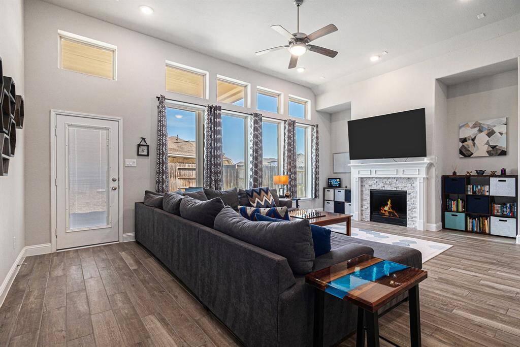 Charming living room with a cozy fireplace, high ceilings, and beautiful views overlooking the backyard.