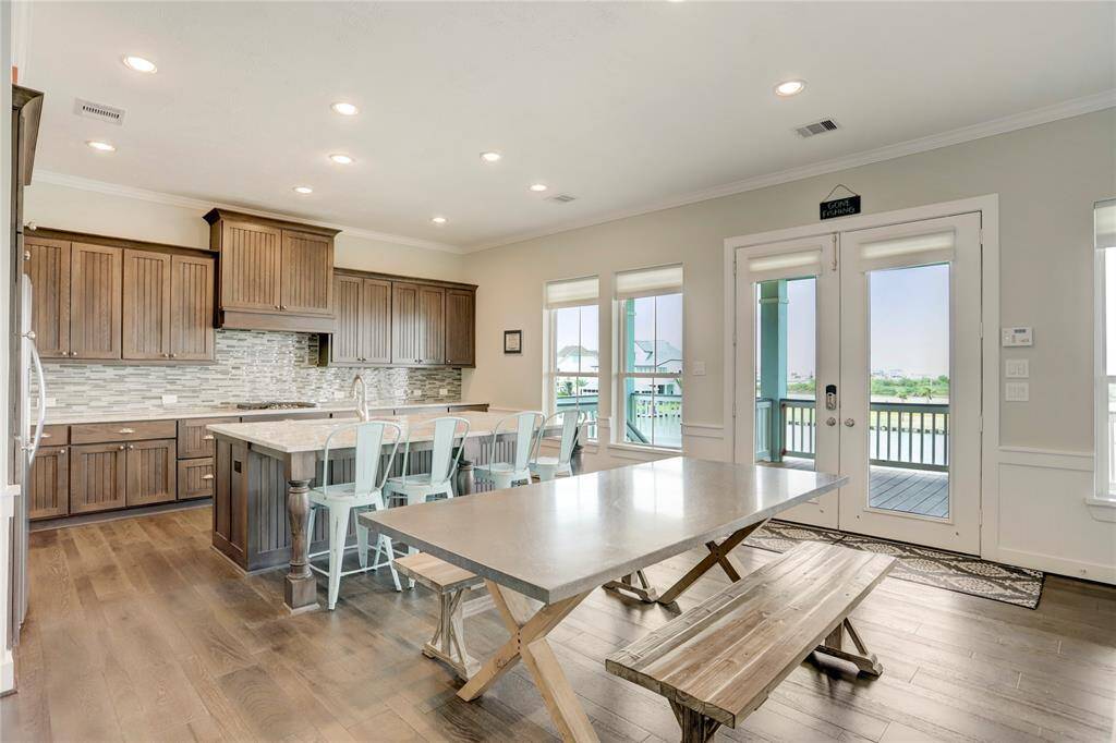 CHEF'S KITCHEN FEATURING DARK WOOD CABINETS AND MODERN STAINLESS STEEL APPLIANCES BLENDSPERFECTLY WITH THE LIGHT WALLS AND COUNTERTOPS. LARGE ISLAND PROVIDES ADDITIONAL SEATING AND PERFECT SPACE SPOT FOR CASUAL MEALS. FRENCH DOORS OPEN TO THE DECK, OFFERING AN EASY FLOW FOR INDOOR-OUTDOOR ENTERTAINING.