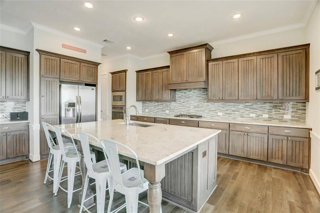 THE KITCHEN FEATURES RICHWOOD CABINETRY WITHVERTICAL PANELING AND ALARGE CENTRAL ISLAND WITHGRANITE COUNTERS OFFERINGPLENTY OF COUNTERSPACE FORFOOD PREPARATION.