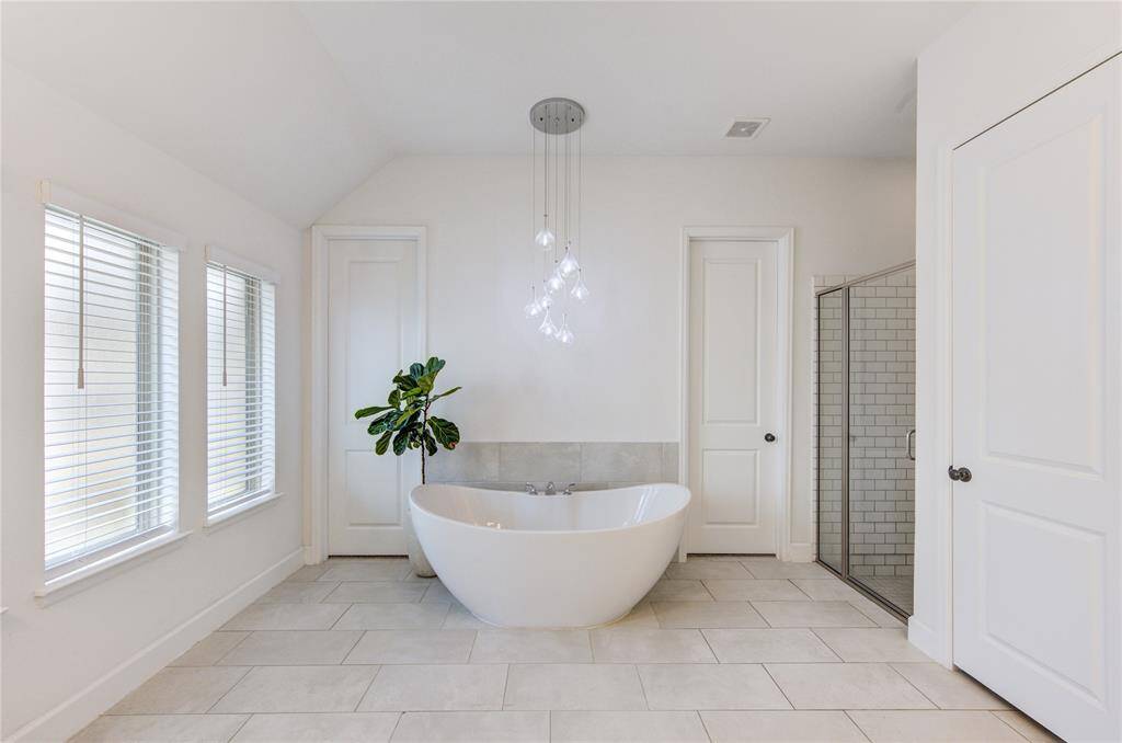 Primary bath includes dual vanities, subway tile, glass enclosed shower, xl freestanding soaking tub, and extended walk-in closet upgrade.
