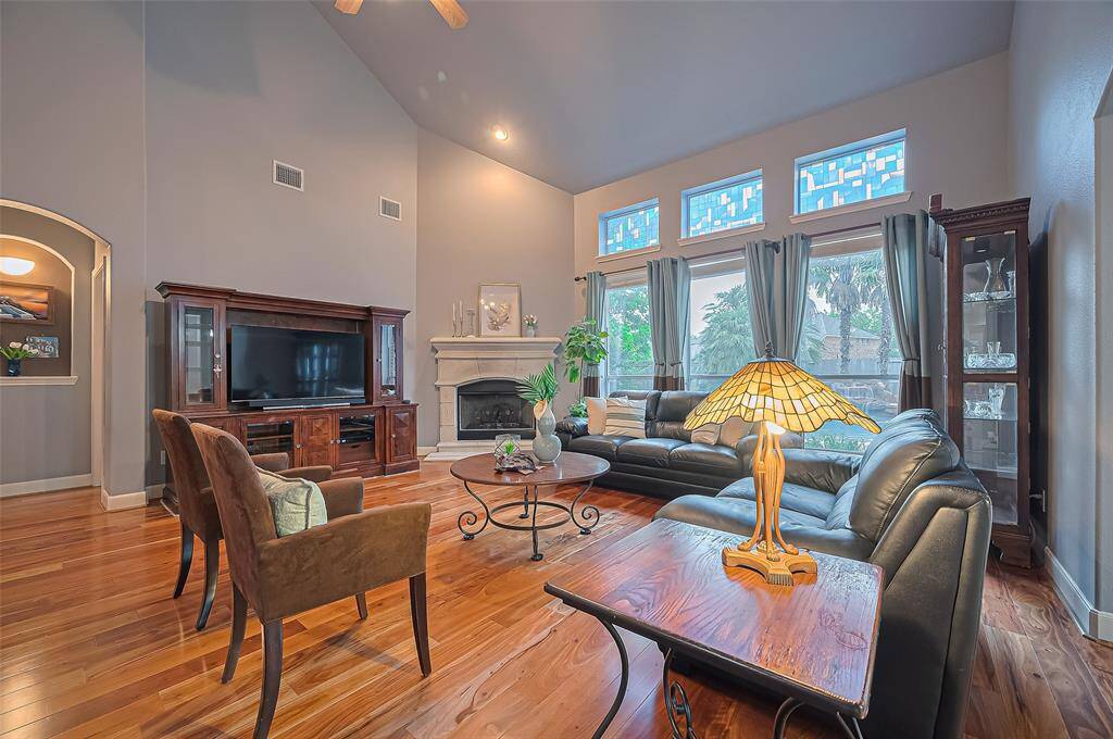 The living room has a cosy stone cast, gas fireplace, high ceilings and a view of the pool. The primary bedroom is through door on the left.