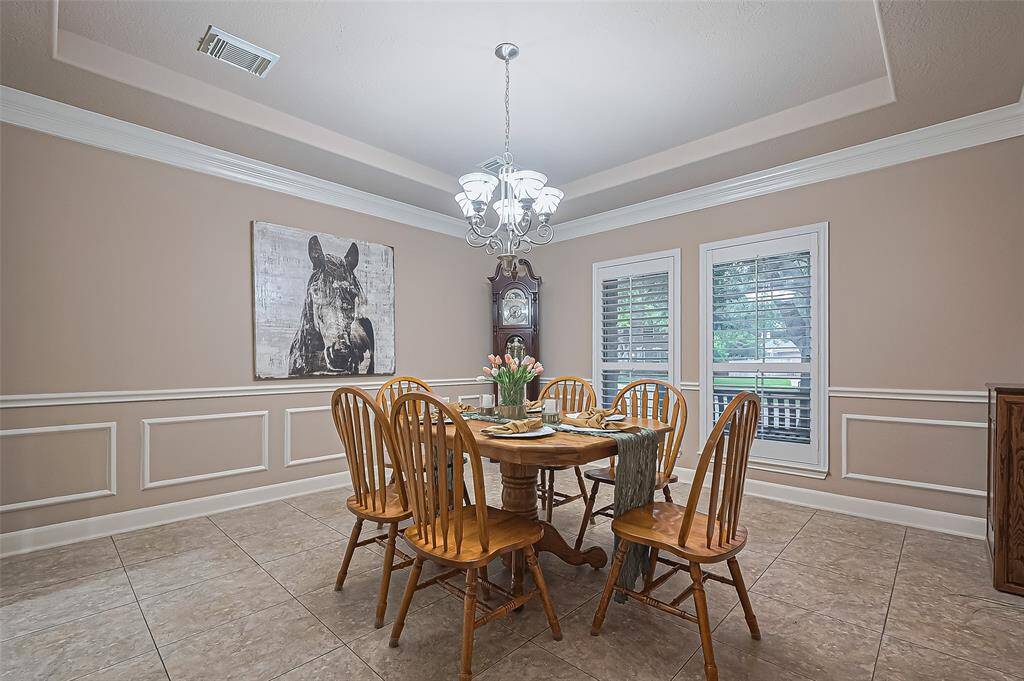 The formal dining room has plantation shutters with a tray ceiling and molding all around the room.