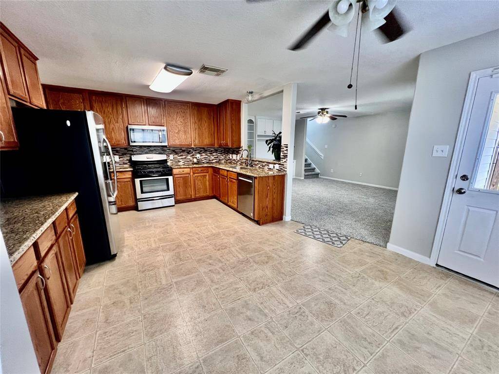 This angle gives you a full view of the kitchen with the opening into the living area, breakfast and the door leading out to the covered back patio.