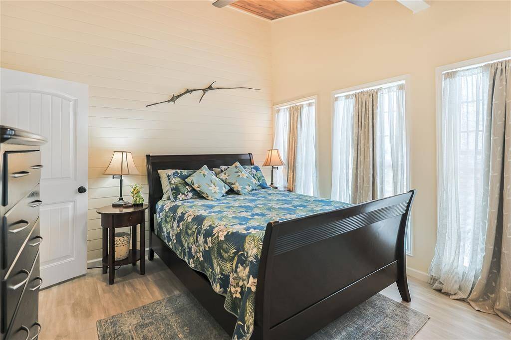 This bright and airy bedroom features soaring ceilings and charming shiplap walls, creating a cozy yet spacious retreat filled with natural light.