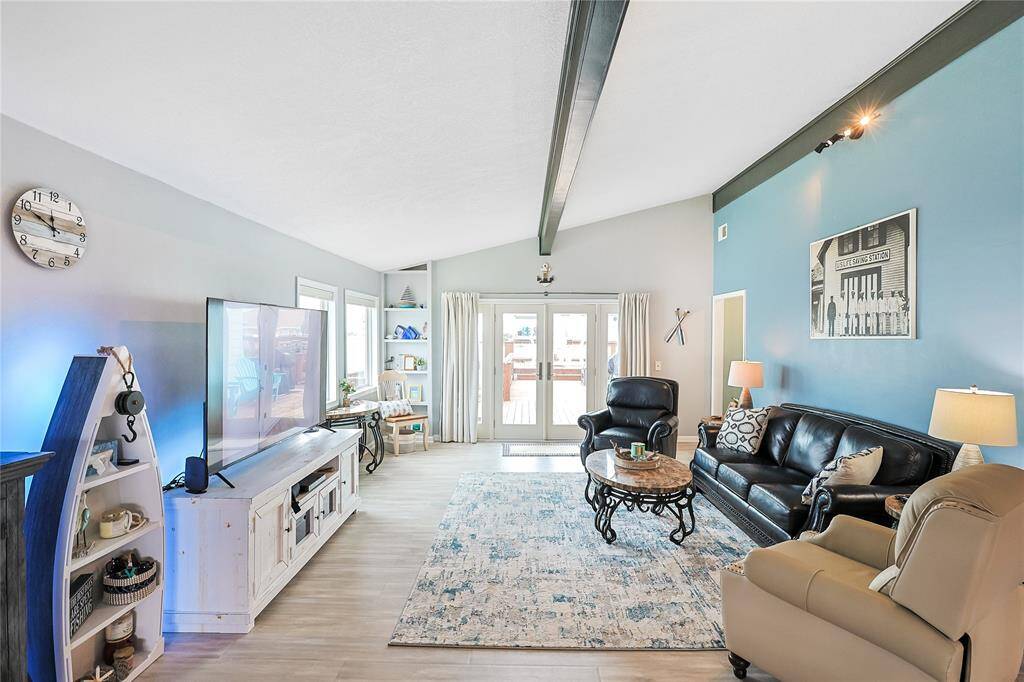 The spacious living area boasts vaulted ceilings and sliding glass doors that open to the deck—blending indoor comfort with outdoor waterfront views.