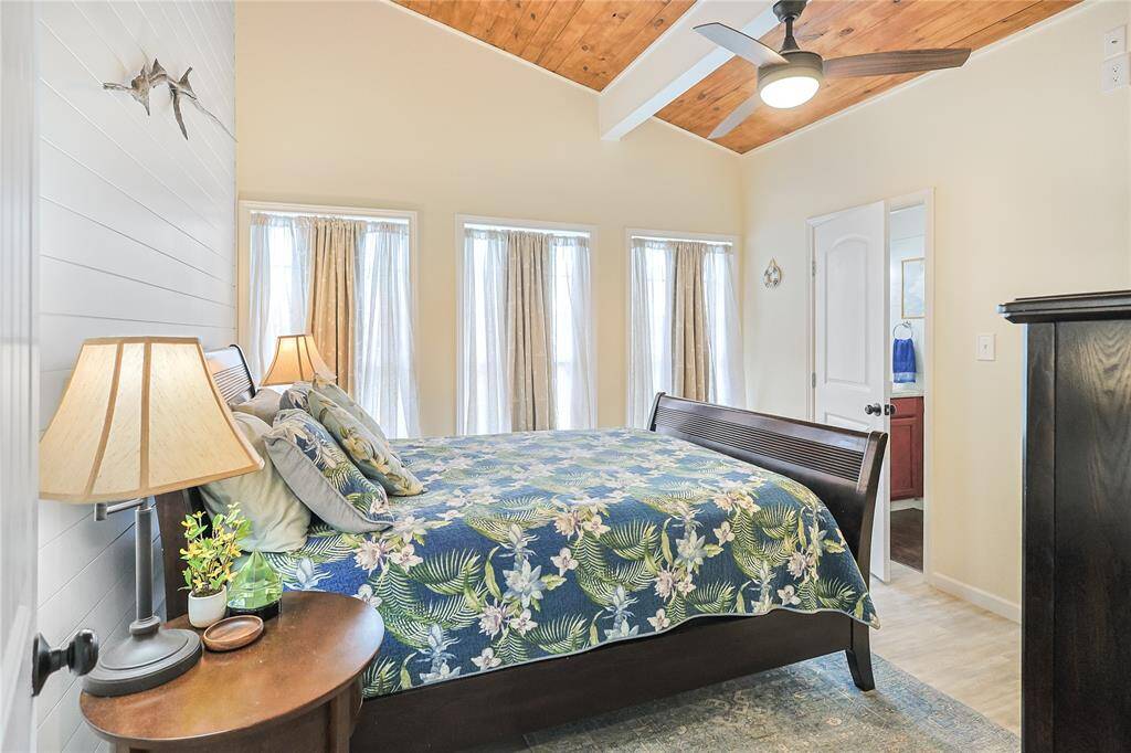 This inviting bedroom showcases a vaulted wood ceiling with exposed beams and crisp shiplap walls, adding warmth and character to your private escape.