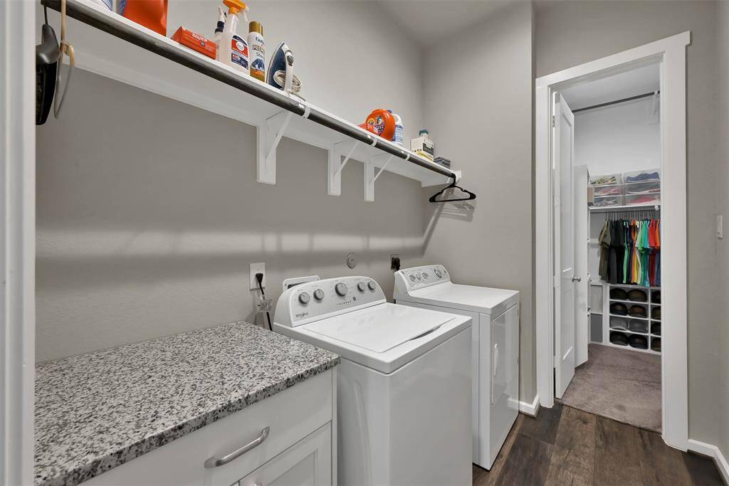 Utility room with granite countertops, shelving for storage. Flows into primary bedroom closet for convenience.