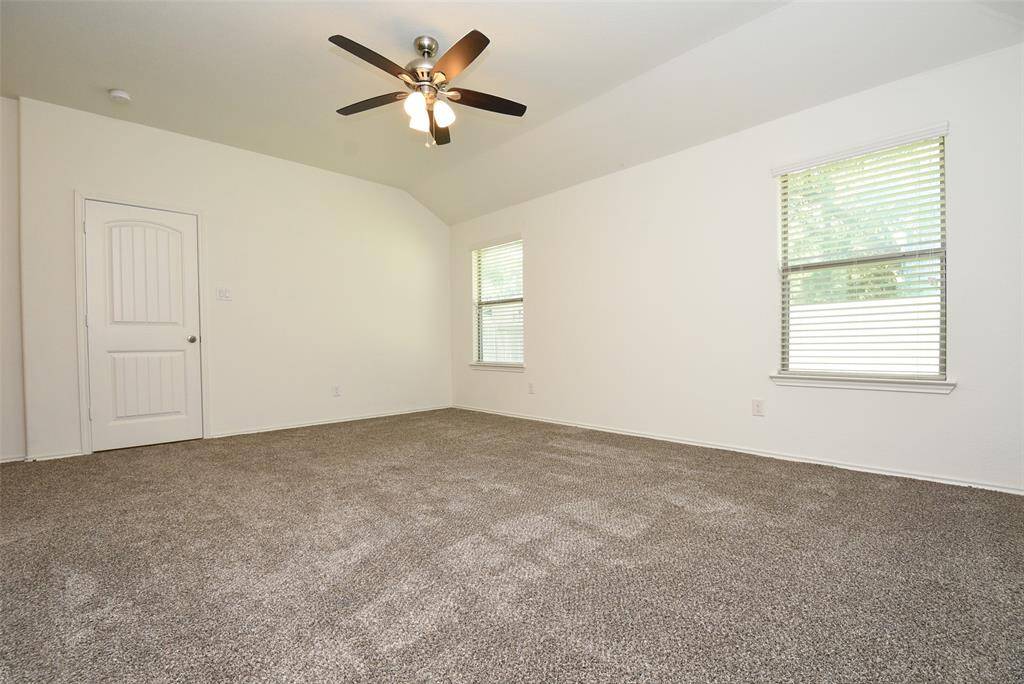 Primary bedroom has ceiling fan, carpet & neutral paint.