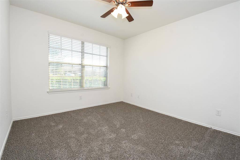 Bedroom 1 features a ceiling fan, carpet & neutral paint.