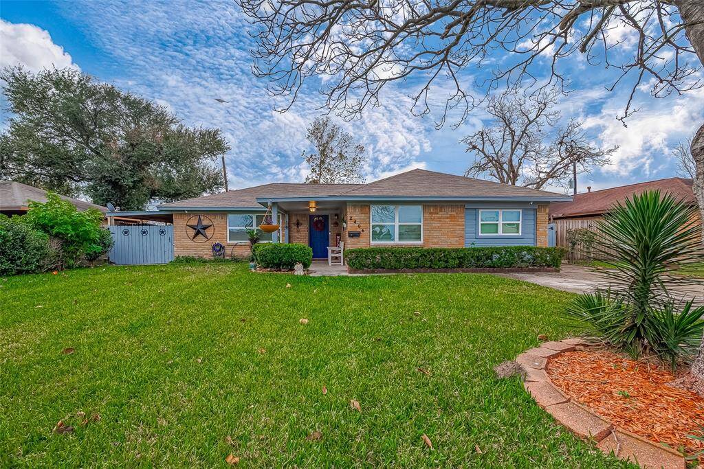 Charming single-story home with a spacious front yard, manicured lawn, and mature trees. Features a welcoming front porch and decorative accents on a brick facade. Ideal for family living in a serene neighborhood.