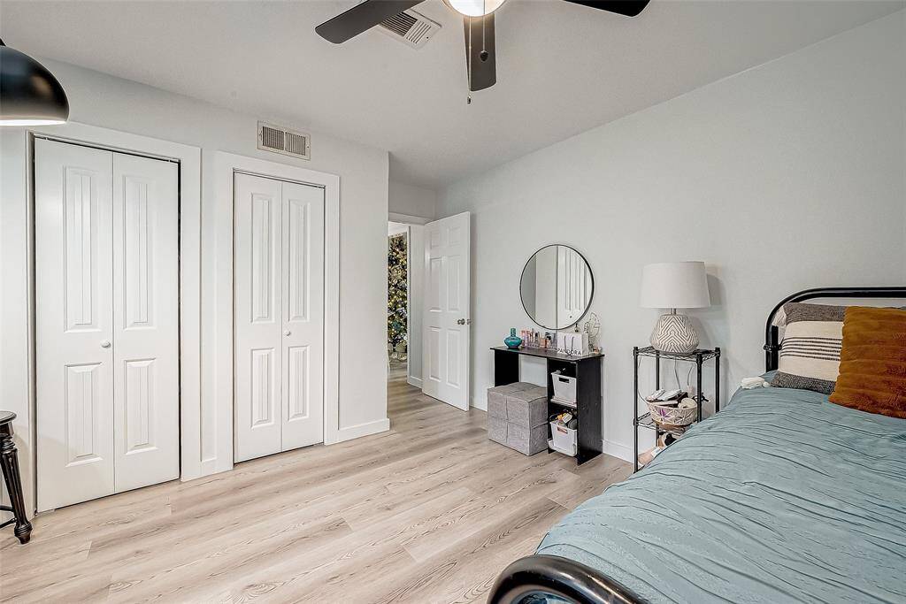 This bedroom features light wood flooring, dual closets with white doors, and a ceiling fan.