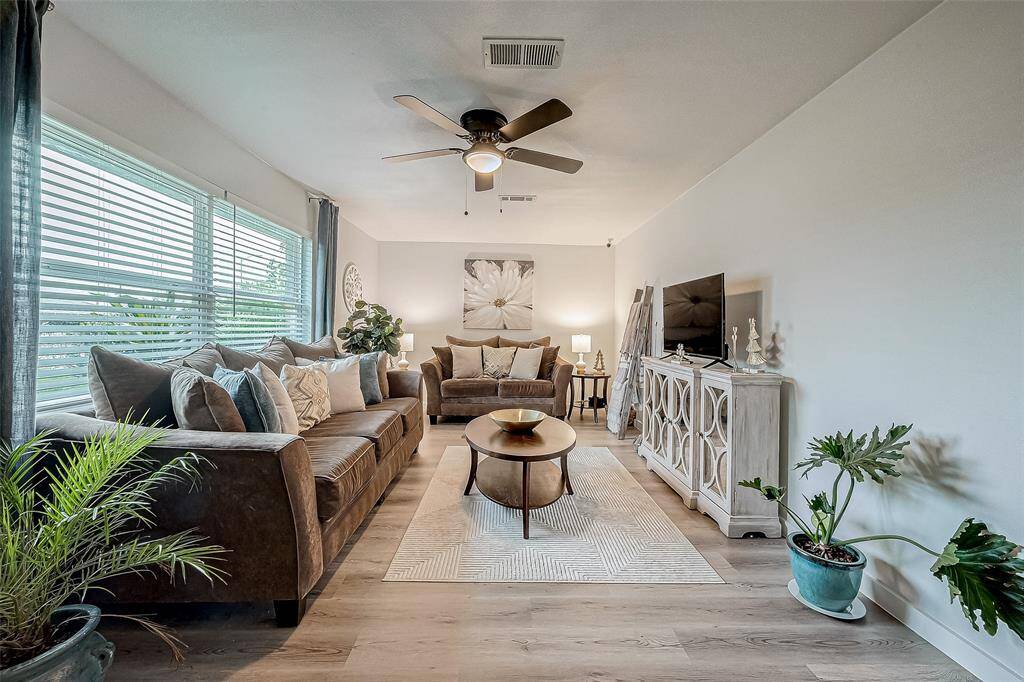 This inviting living room features large windows for natural light, a ceiling fan, and elegant decor.