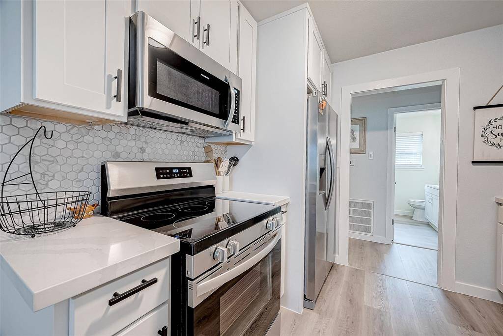 Modern kitchen with sleek stainless steel appliances, white cabinetry, and a stylish hexagonal tile backsplash.