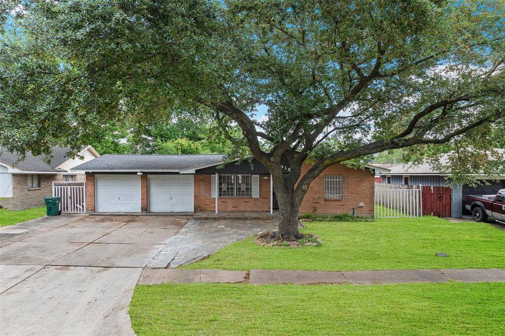 Charming single-story brick home with a large, mature tree providing shade in the front yard. Features a two-car garage and a spacious driveway. The yard is well-maintained with lush green grass, offering great curb appeal.