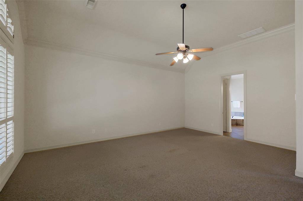 The primary suite has double crown molding, ceiling fan and private en-suite.
