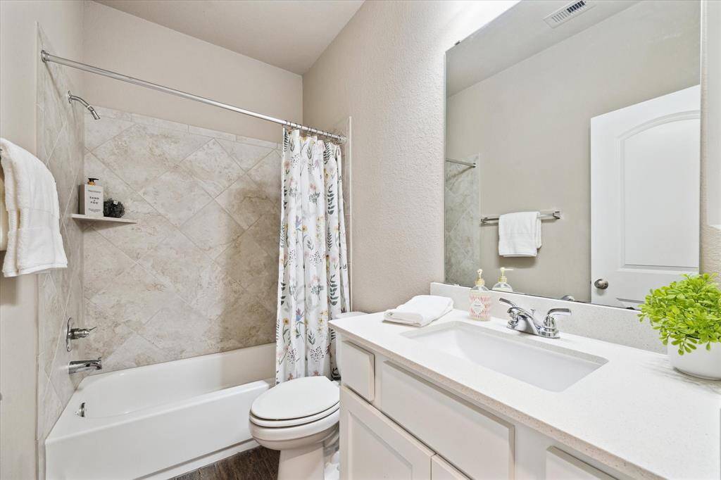 Hall bath has a tub/shower combo for guests and the secondary bedrooms. Quartzite countertops and diagonally placed oversized tiles are extra touches of refinement.