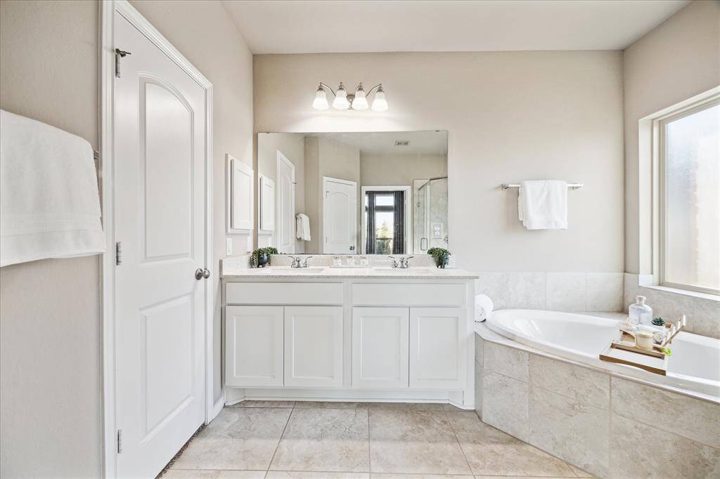 Double vanity, oversized marble flooring and quartzite countertops, with a rain glass window give off spa vibes.