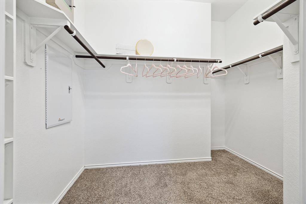 Primary closet with shelving and clothes' rods for ample storage solutions. Alarm home base located here.