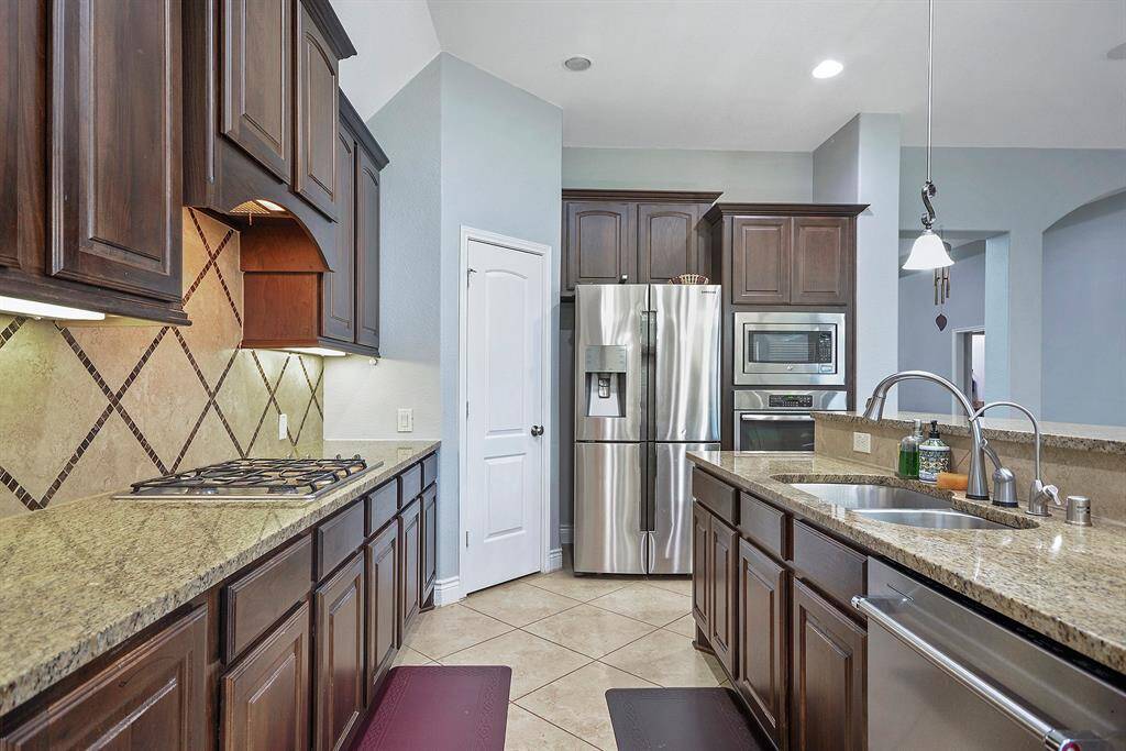 This Kitchen has it all light color granite counter tops, endless counter space, rich stained cabinets, pendent lighting for the island, stainless steel matching appliances, and beautiful tile backsplash.