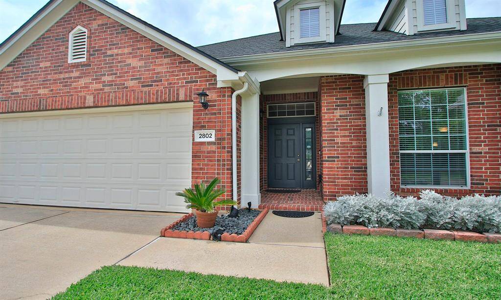 An impressive front elevation adorned with a beautiful landscape and charming brick covered front porch.