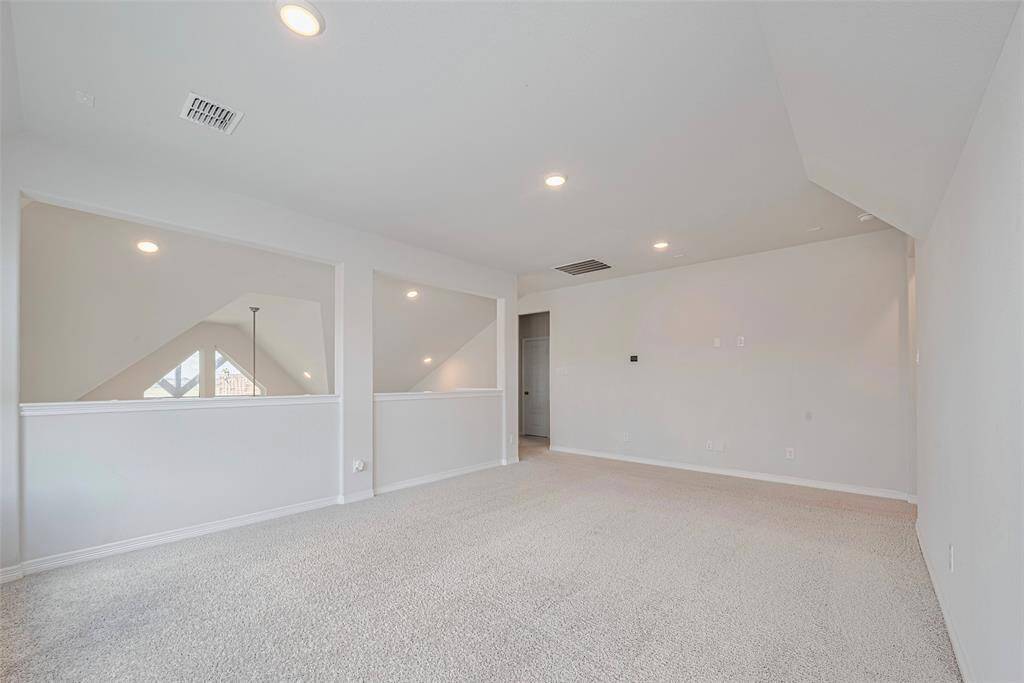 Bright and spacious larea with soft carpeting, recessed lighting, and three large windows, offering a versatile space overlooking the main level below.