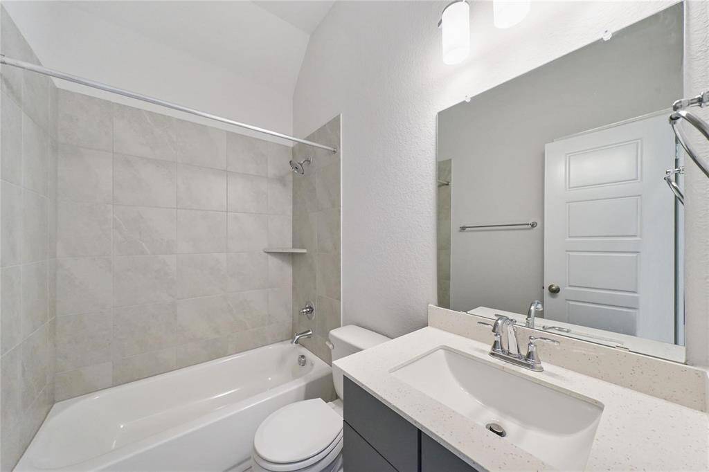 Guest bathroom downstairs features a bright & modern design with a bathtub and shower, a sleek vanity with a large mirror & contemporary fixtures.