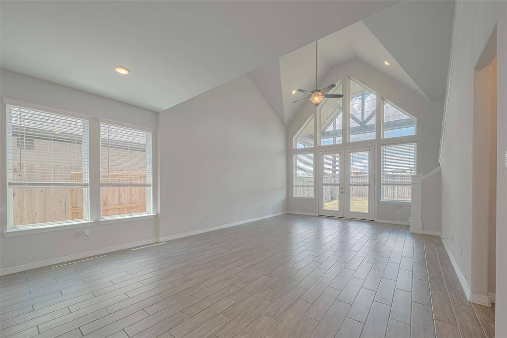 Stunning high vaulted ceilings, large windows for abundant natural light, and sleek tile flooring. A modern ceiling fan complements the bright, open space. Perfect for a contemporary feel.