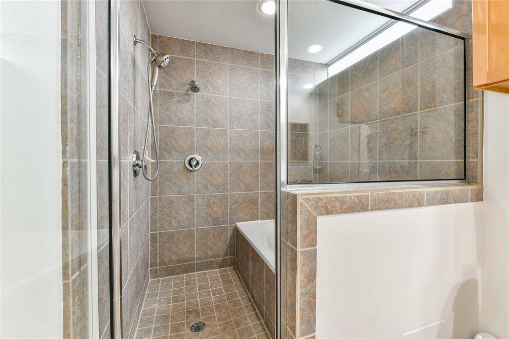 A shower room featuring double shower heads and a soaking tub!
