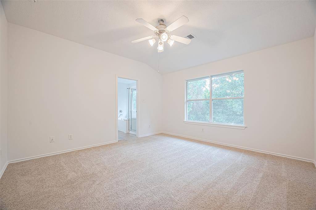 Spacious primary bedroom with direct access to a bright, attached bathroom.