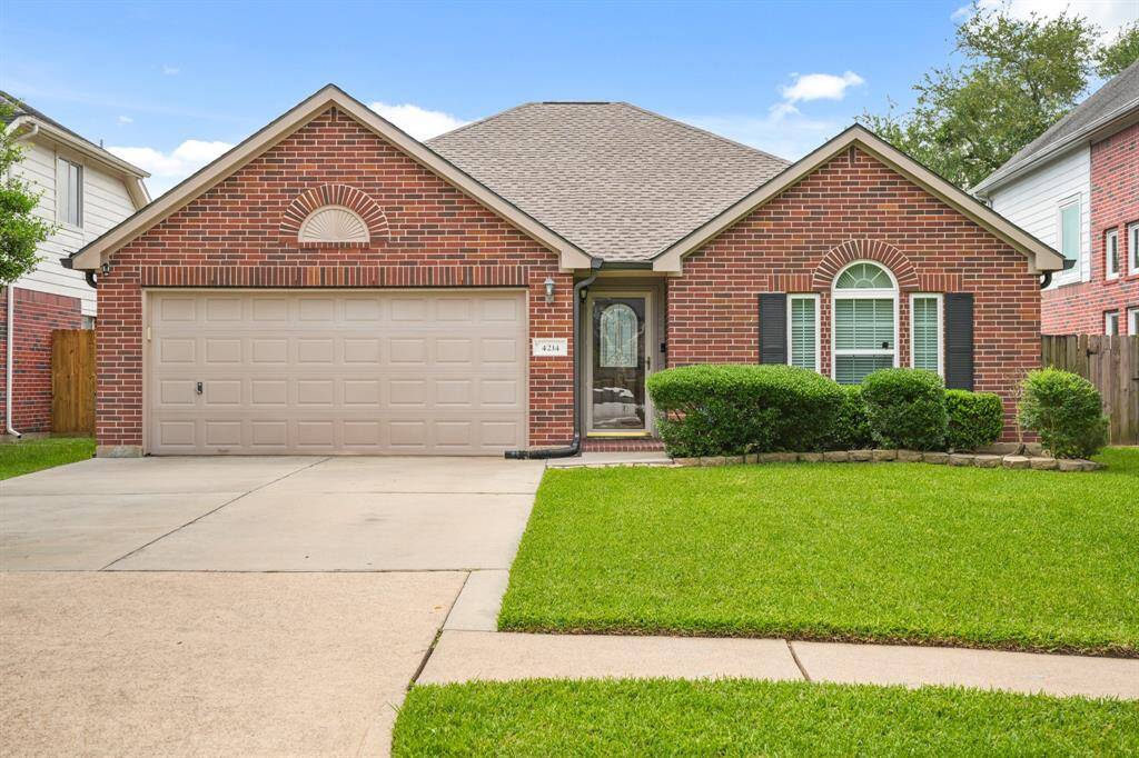 This charming brick home features a classic gable roof, a neatly landscaped front yard, and a spacious two-car garage. The entryway, framed by elegant windows and shutters, adds to the curb appeal. Ideal for a welcoming and comfortable living space.