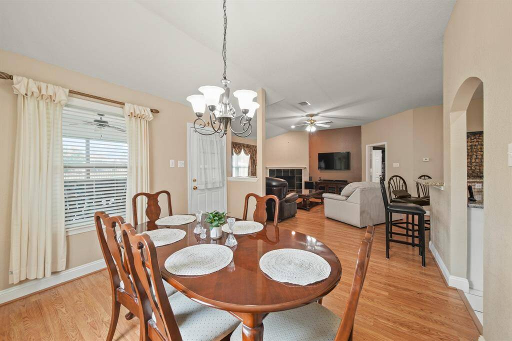 This photo showcases an open-concept living and dining area with hardwood flooring, neutral walls, and ample natural light.