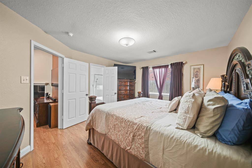 This primary bedroom features a cozy atmosphere with warm wood flooring and ample natural light.  It includes an en-suite bathroom.