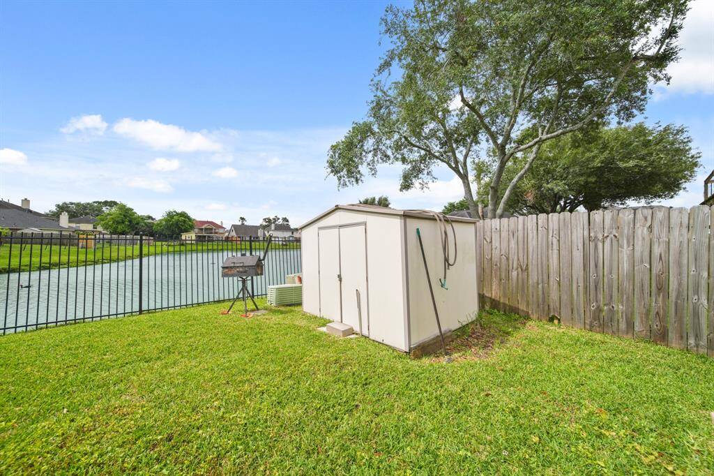 Spacious and fenced backyard surrounded by lush greenery, offering a serene and private outdoor retreat.  Convenient outdoor storage.