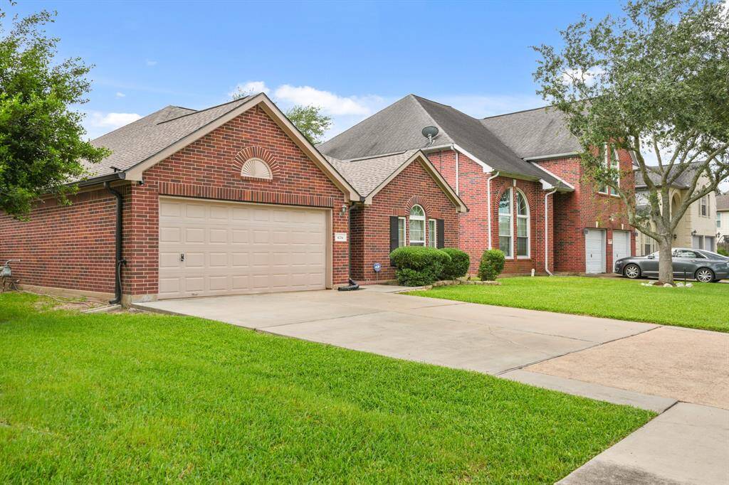Charming brick home with a spacious two-car garage, well-maintained lawn, and mature trees. Features a classic roofline and stylish arched windows for added curb appeal.
