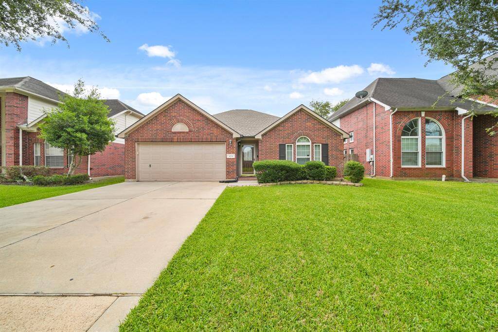 This photo showcases a charming single-story brick home with a well-maintained front yard. It features a two-car garage with double-wide driveway convenient for plenty of parking.