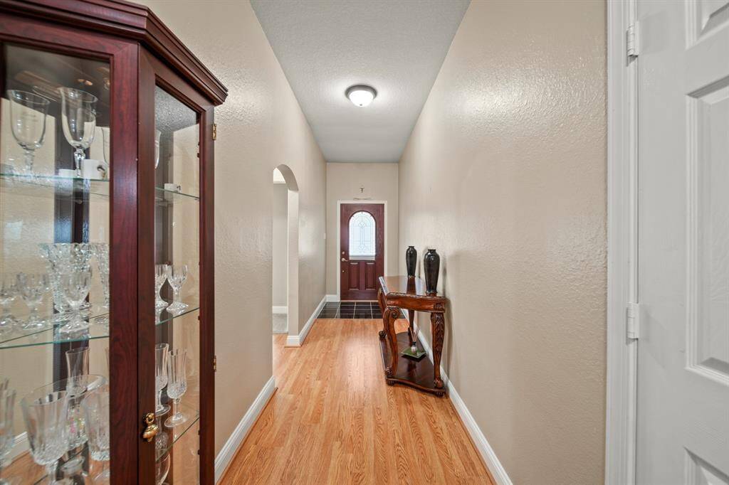 A welcoming entryway with hardwood flooring.  The hallway leads to a door with a glass inset, offering a warm and inviting atmosphere.