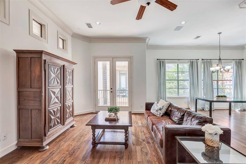 Large windows and French doors provide ample natural light, complemented by a ceiling fan and elegant chandelier. Ideal for a cozy yet sophisticated atmosphere.