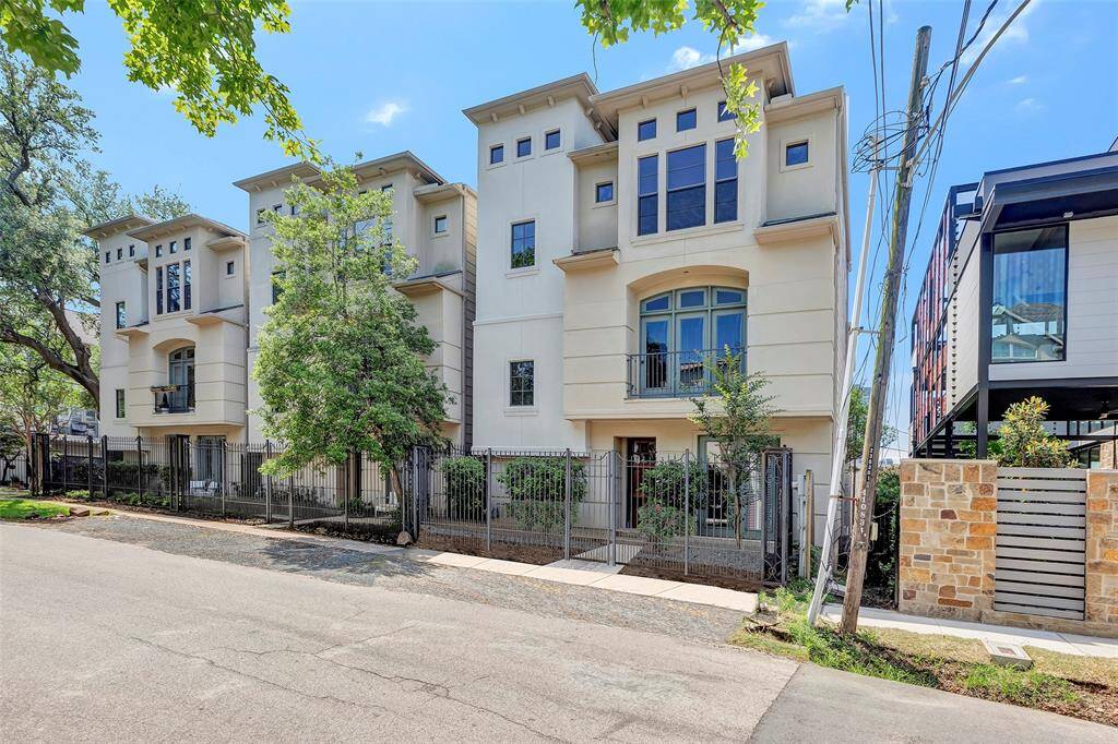 Modern three-story townhouse with a sleek design, featuring large windows and a gated entry. The property is lined with trees, offering a mix of urban and natural appeal. Ideal for buyers seeking contemporary living in a vibrant neighborhood.