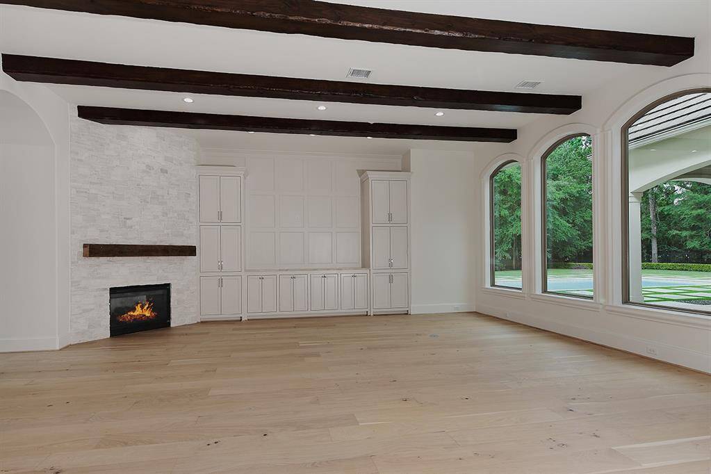 The family room with gas fireplace, wood beam ceiling and new custom built-ins is framed with windows, providing pool and golf course views.
