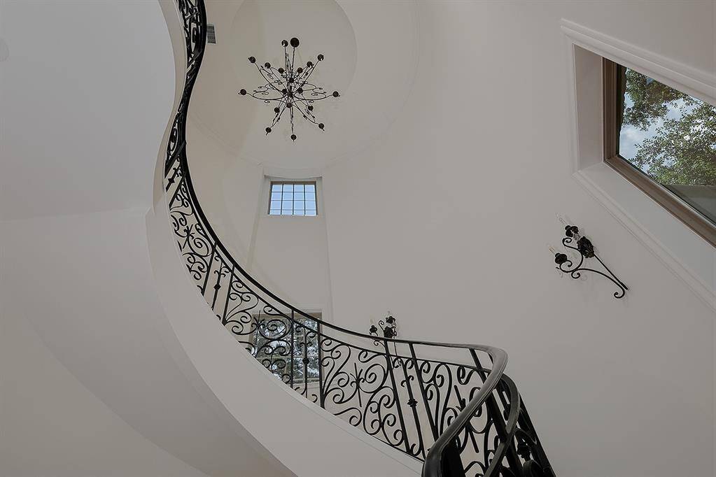 Exquisite detail in the wrought iron staircase with designer chandelier and sconces.