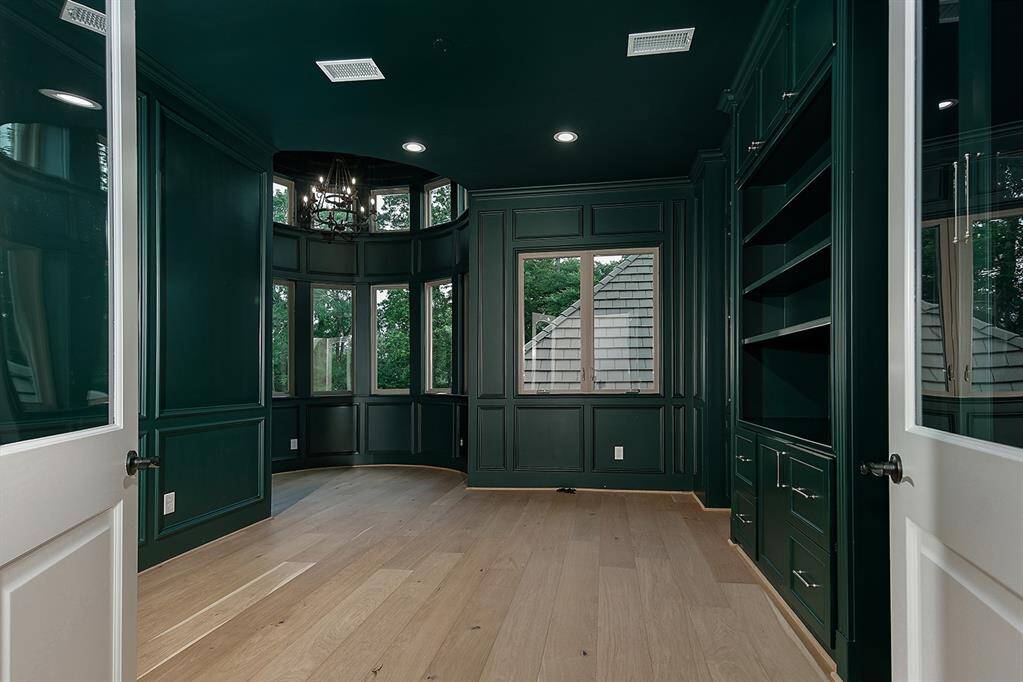 The study with corner rotunda, has been painted a deep hunter green to accentuate the verdant trees and golf course in the background. Custom built-ins and large windows complete this handsome office space.