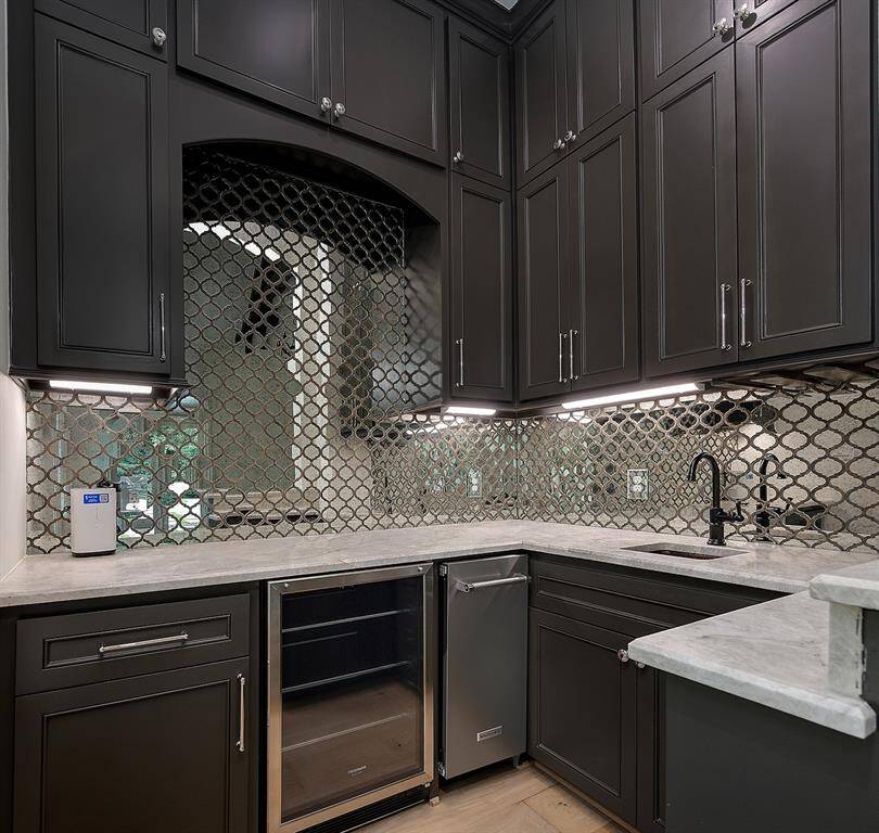 The wet bar in the downstairs game room has a brand new ice maker, fridge, antique mirrored backsplash and quartz counters.