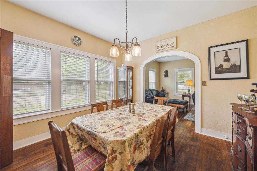 Formal dining room filled with natural light from three sets of double windows. The original archway and continuous hardwood floors carry the charm and flow throughout the home.