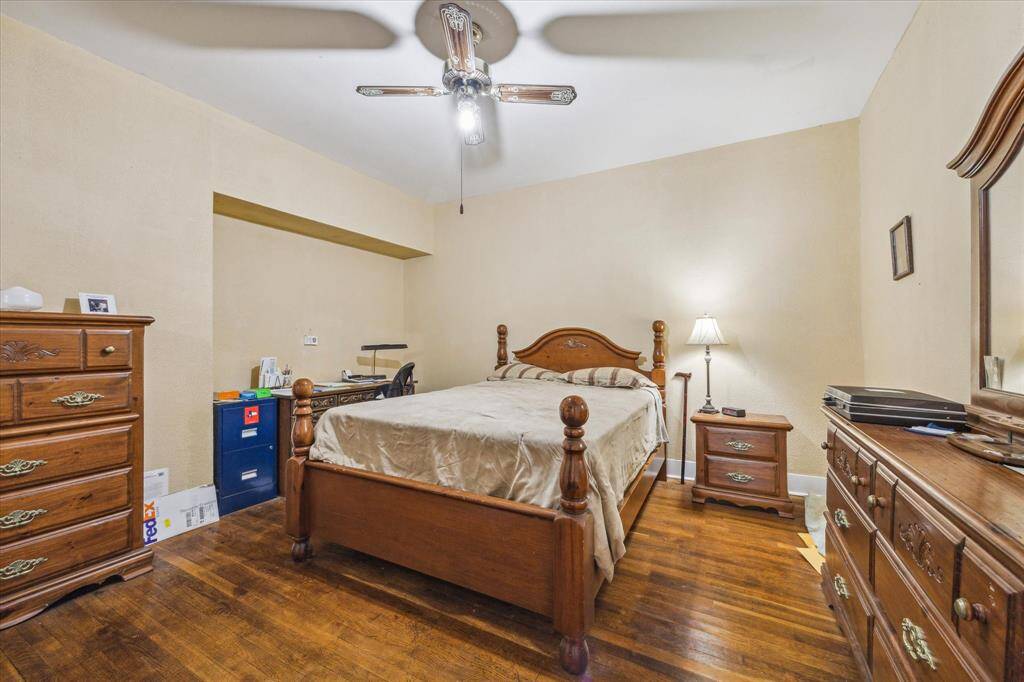 Tucked off the hall near the kitchen, this bedroom features a built-in wall nook that adds charm and character. Flawless wood floors and a ceiling fan complete the space.