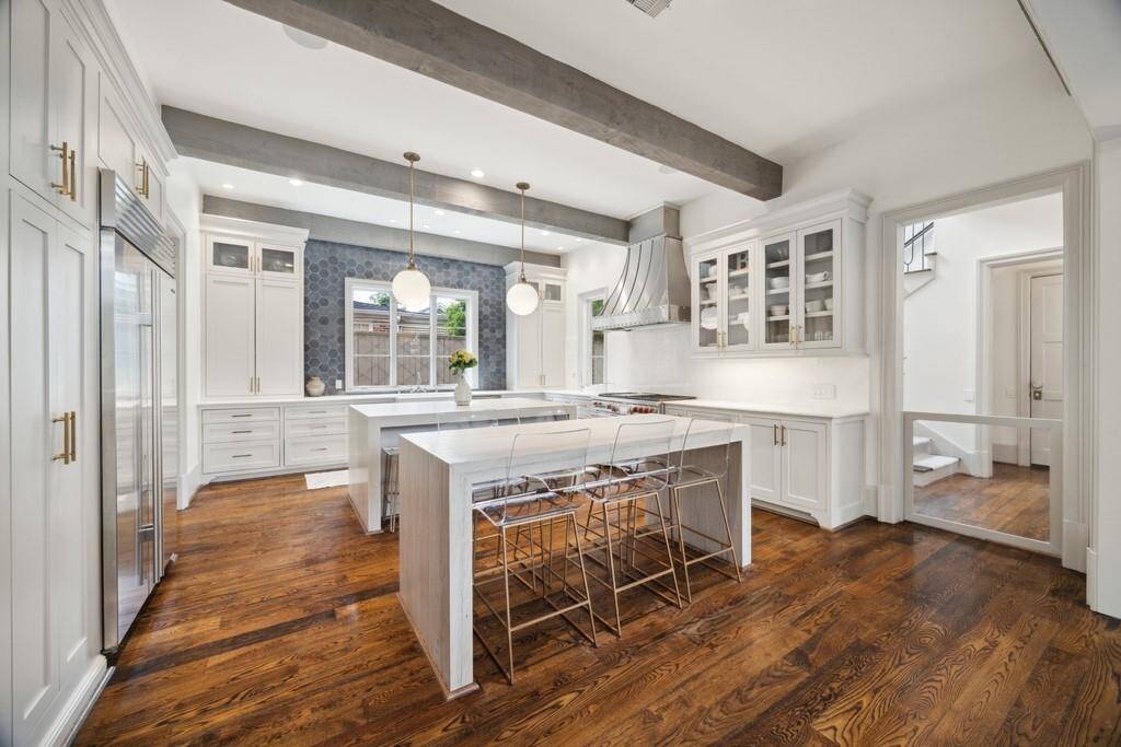 Another view of the kitchen showcases the functional elegance of dual islands—perfect for prepping, serving, and gathering. Just steps away, the back staircase offers easy access to the upper level.