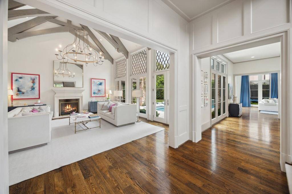 This view showcases the effortless flow from the formal living area into a sunlit hallway that leads to a private home office and a separate playroom or hangout space.