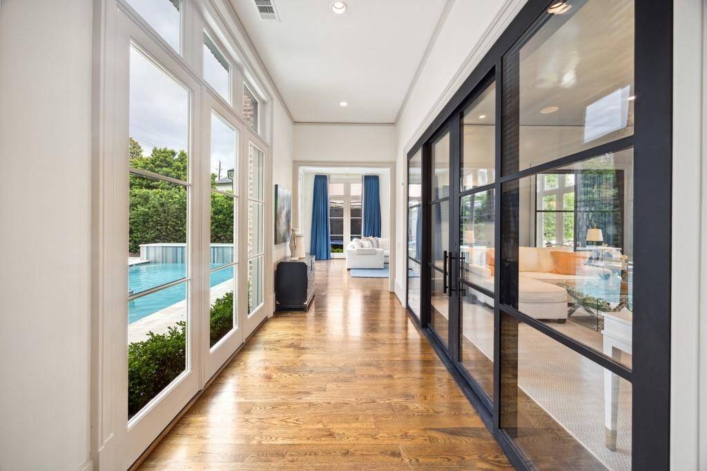 This light-filled hallway offers serene views of the pool through a wall of windows, while sleek steel-framed doors reveal a private home office.