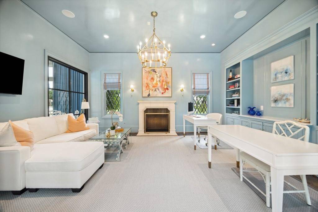 This elegant home office features high-gloss lacquered walls and ceiling, creating a bold yet calming atmosphere. Thoughtfully designed with dual workstations, built-ins, a cozy fireplace, and a spacious lounge area.