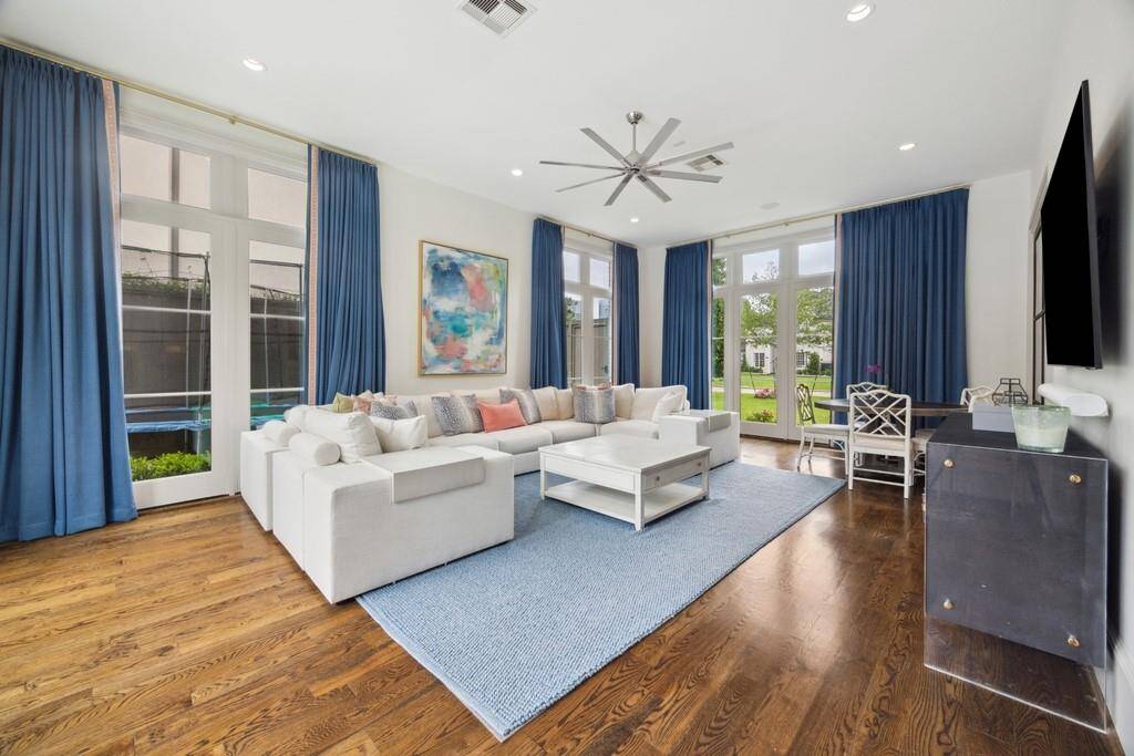 This downstairs playroom and hangout space is filled with natural light, featuring walls of windows. Warm wood floors and a casual dining or game nook make it the perfect spot for relaxing, playing, or hosting friends and family.