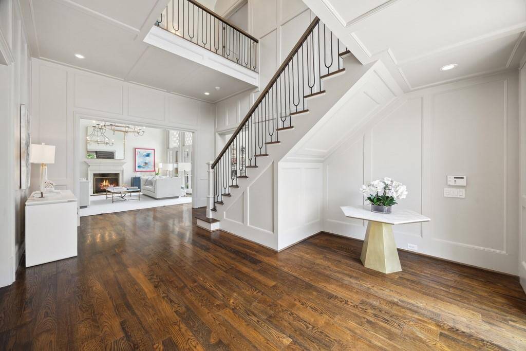 The entry features detailed millwork, warm hardwood floors, and a striking staircase that leads to the home’s second level.